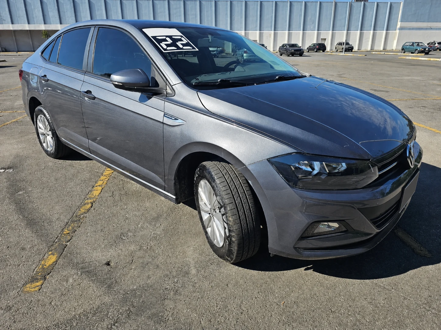 Volkswagen Virtus cinza visto de lado em pátio aberto